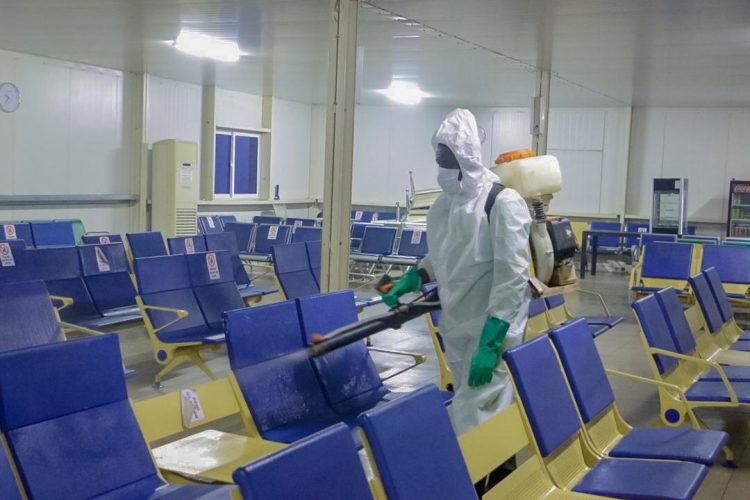 Técnico con traje de protección aplicando un tratamiento con mochila pulverizadora en una sala de espera