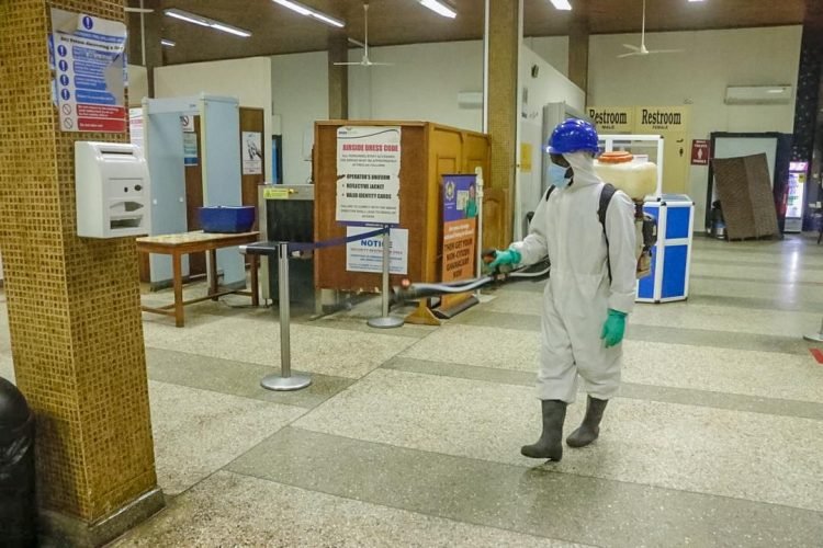 Técnico con traje de protección y mochila pulverizadora tratando el interior de un edificio